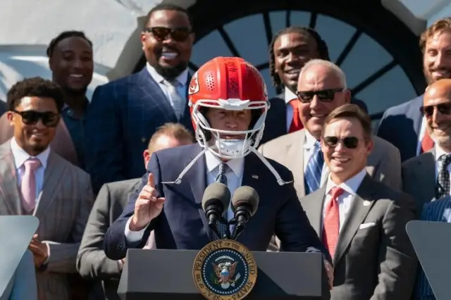 "President Biden proudly dons a Kansas City Chiefs helmet during the team's visit to the White House, commemorating their Super Bowl triumph."